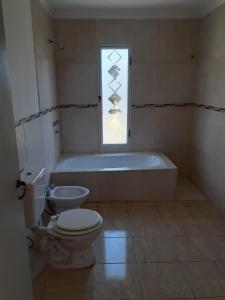 a bathroom with a tub and a toilet and a window at beatiful house in Vuelta de Obligado