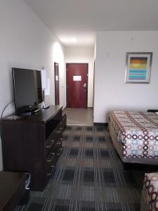 a hotel room with a bed and a flat screen tv at Days Inn by Wyndham Alva in Alva