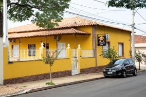 una casa amarilla con un coche aparcado delante de ella en Casarao Hostel - Analandia SP en Analândia