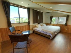 本部的住宿－美麗海村旅館，卧室配有一张床和一张桌子及椅子