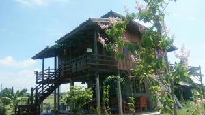 une cabane dans les arbres avec un balcon et quelques fleurs dans l'établissement Ban Suan Khun Yai, à Phra Nakhon Si Ayutthaya