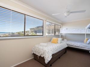 1 dormitorio con 2 camas y 2 ventanas en Casa Moana, en Gerringong