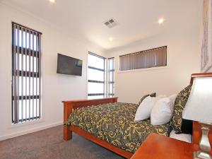 a bedroom with a bed and a tv on the wall at ✿Stylish Townhouse; with King Bed, NBN, Netflix, WIFI in Christies Beach