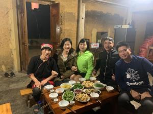 a group of people sitting around a table with food at Mun Homestay in Ha Giang