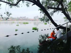 dos personas sentadas en las escaleras cerca de un lago en River CoCo @ Amphawa, en Samut Songkhram