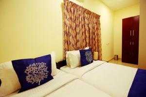 a hotel room with a bed with blue and white pillows at Geo Fort Home - Fortkochi in Fort Kochi
