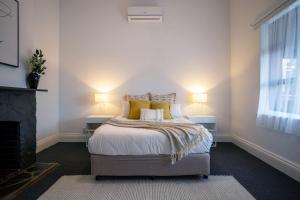 a bedroom with a bed with yellow pillows and a fireplace at Beach & Pines Glenelg in Glenelg +17 photos