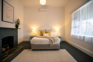 a bedroom with a bed and a fireplace at Beach & Pines Glenelg in Glenelg