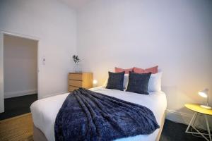 a bedroom with a large bed with a blue blanket at Beach & Pines Glenelg in Glenelg