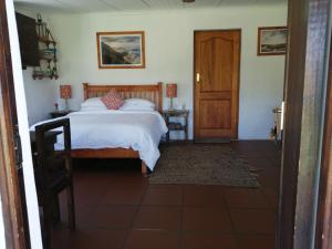 a bedroom with a bed and a wooden door at Hermitage Huisies in Swellendam