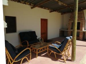 a patio with chairs and a table and a fireplace at Hermitage Huisies in Swellendam