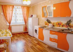 a kitchen with orange and white cabinets and a dishwasher at Dekabrist Apartment on Proezzhaya 25 in Chita