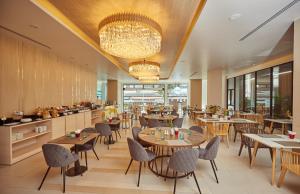 a restaurant with tables and chairs and a chandelier at Pattaya Sea View Hotel - SHA Extra Plus in Pattaya