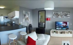 a living room with a white couch and a kitchen at Sea Spray in Bloubergstrand