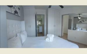 a white bed with a teddy bear sitting on it at Sea Spray in Bloubergstrand +17 photos