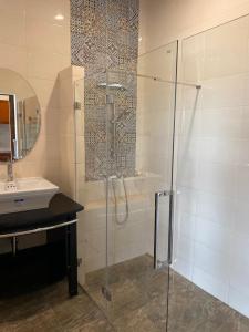 a bathroom with a glass shower and a sink at Damnoen Care Resort in Damnoen Saduak