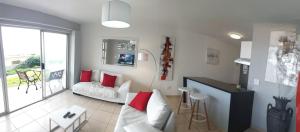a living room with a white couch and red pillows at Sea Spray in Bloubergstrand