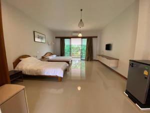 a bedroom with two beds and a television in it at Damnoen Care Resort in Damnoen Saduak