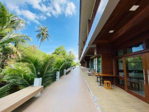 Damnoen Care Resort في دامنون سادواك: ممر لمبنى فيه كراسي واشجار النخيل