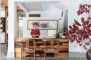 a woman standing behind a counter with two chairs at Qingshanshe Hotel in Guilin