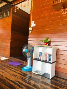 a room with a book shelf and a fan at Banthai Guesthouse in Phetchaburi