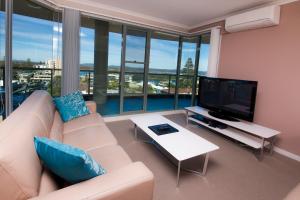 a living room with a couch and a flat screen tv at Sails Apartments in Forster
