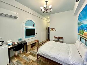 a bedroom with a bed and a desk and a tv at Moon Bay Coastal Hotel in Xincheng