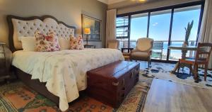 a bedroom with a large bed with a large window at On the Beach Guesthouse Jeffreys Bay in Jeffreys Bay