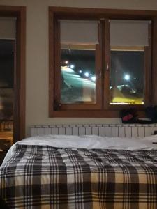 a bed with a plaid blanket in a room with windows at Apartment 216 NiM Vučko in Jahorina