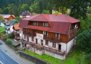 una casa grande con techo rojo al lado de una calle en Pensiunea Panorama Elcomex, en Băile Tuşnad