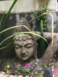 a statue of a head in a garden at Nadialit in Seminyak
