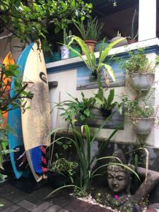 una tavola da surf seduta accanto a una statua e a piante di Nadialit a Seminyak