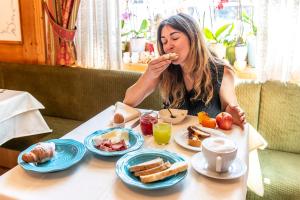 een vrouw die aan een tafel zit te ontbijten bij Hotel Arcangelo in Pellizzano