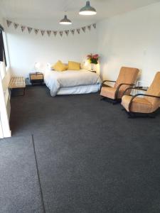 a bedroom with a bed and two chairs at Clifden Pitstop in Eastern Bush