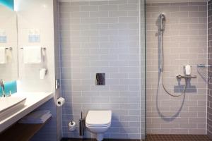 ein Bad mit einer Dusche, einem WC und einem Waschbecken in der Unterkunft Holiday Inn Express Munich - Olympiapark, an IHG Hotel in München