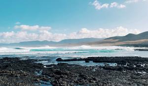 a rocky beach with the ocean and mountains in the background at CASA MAREA in Caleta de Caballo