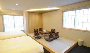 京都市にあるHIZ HOTEL Kyoto-Nijo Castleのベッド、テーブル、椅子が備わるホテルルームです。