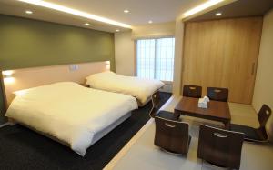 京都市にあるHIZ HOTEL Kyoto-Nijo Castleのベッド2台、テーブルと椅子が備わるホテルルームです。