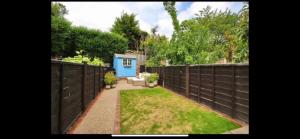 a backyard with a fence and a blue shed at Cosy and Contemporary Cottage in Uckfield