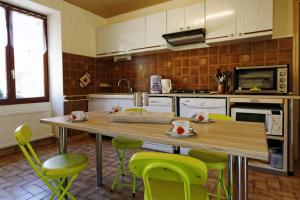 une cuisine avec une table en bois et des chaises vertes dans l'établissement La Garçonnière, à Treigny