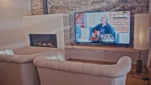 a living room with a tv and a fireplace at Hotel Els Caçadors de Ribes in Ribes de Freser