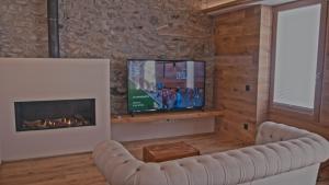 a living room with a fireplace and a tv at Hotel Els Caçadors de Ribes in Ribes de Freser