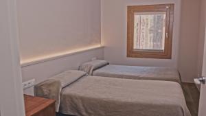 two beds in a small room with a window at Hotel Els Caçadors de Ribes in Ribes de Freser