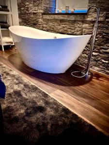 a white bath tub sitting on a wooden floor in a bathroom at TRENDY HOUSE 193 in Mátranovák