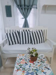 a white couch with a table with a pot of flowers on it at Prathana Garden Beach Resort in Hua Hin