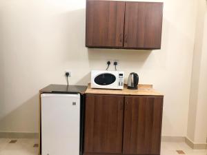 a kitchen with a microwave and a refrigerator at رايتنا للوحدات السكنية المفروشة in Riyadh