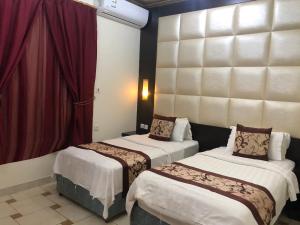 2 camas en una habitación de hotel con cortinas rojas en رايتنا للوحدات السكنية المفروشة, en Riad