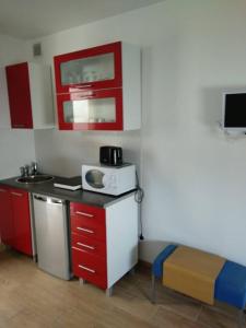 Kuchnia wyposażona jest w czerwono-białe szafki oraz kuchenkę mikrofalową. w obiekcie CMG Porte de Châtillon Malakoff II w mieście Malakoff
