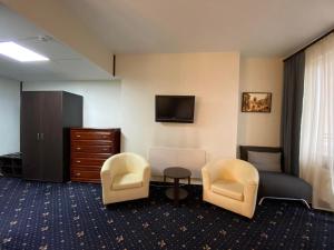 キーウにあるアイリスホテルズの椅子2脚、ベッド1台、テレビが備わる客室です。