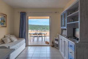 a living room with a bed and a television and a table at Baia de Bahas Residence in Golfo Aranci